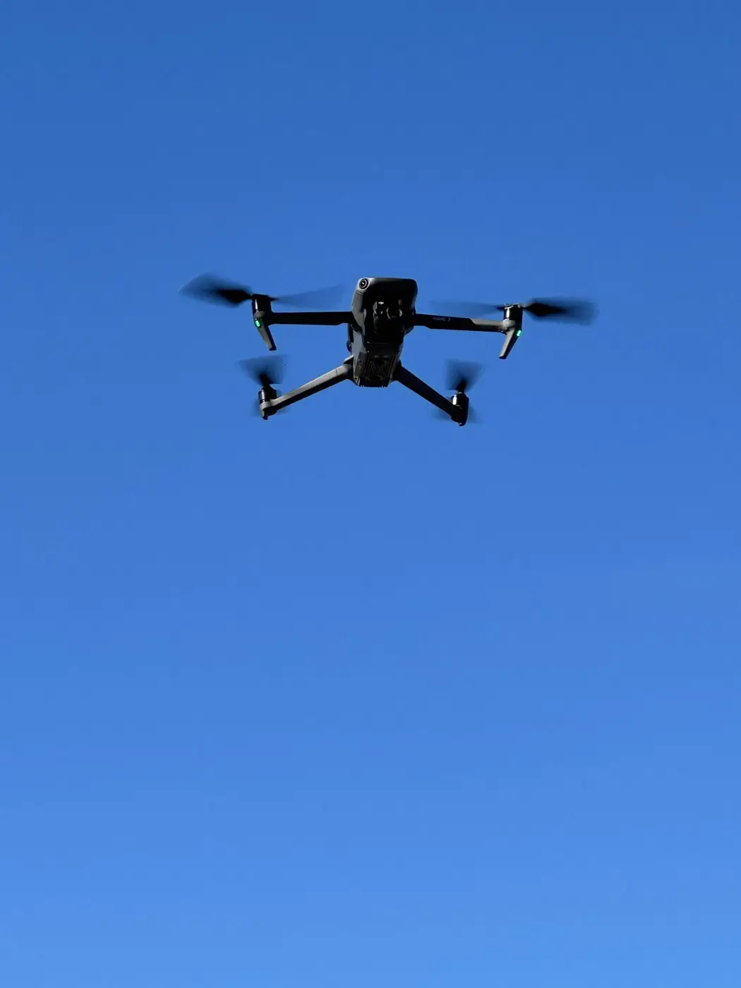 DJI Mavic-drönare i luften under takinspektion mot klarblå himmel